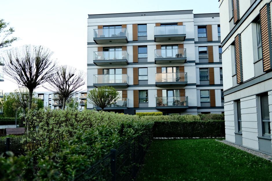 Apartment building behind a clipped hedge and lawn