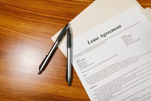 Lease agreement pages and two pens on a wooden desk