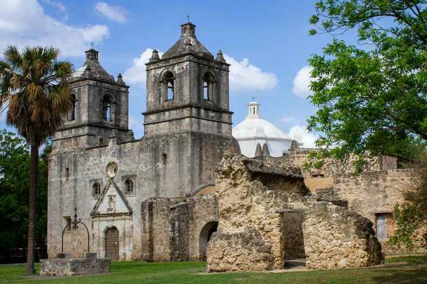 Historic mission church with twin bell towers and palms in San Antonio