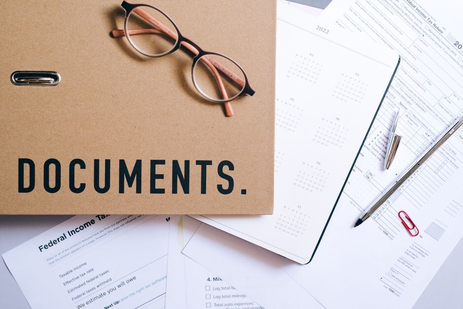 Document folder, reading glasses and printed forms on a desk