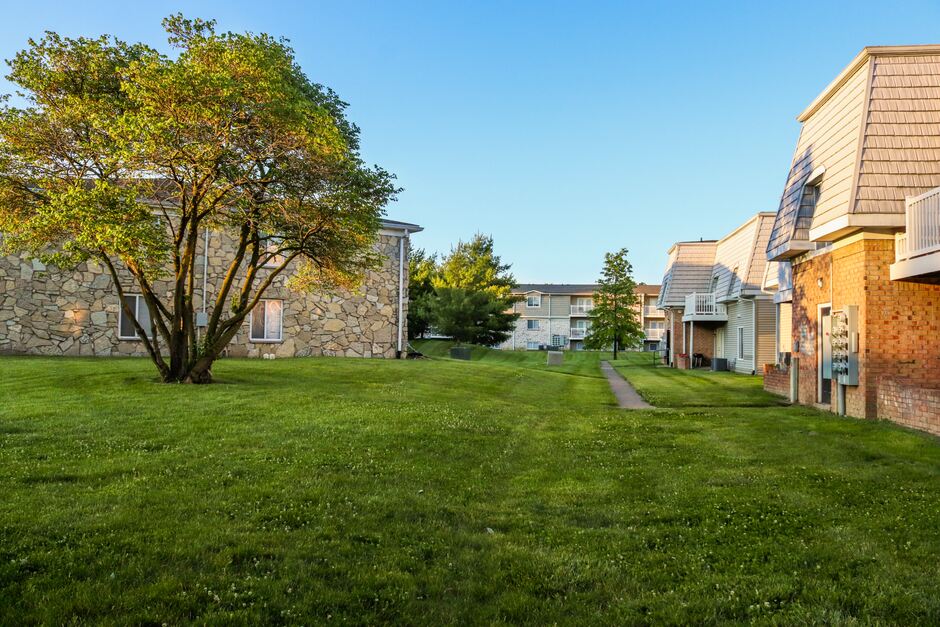 Garden apartment buildings around a grass lawn and shade tree