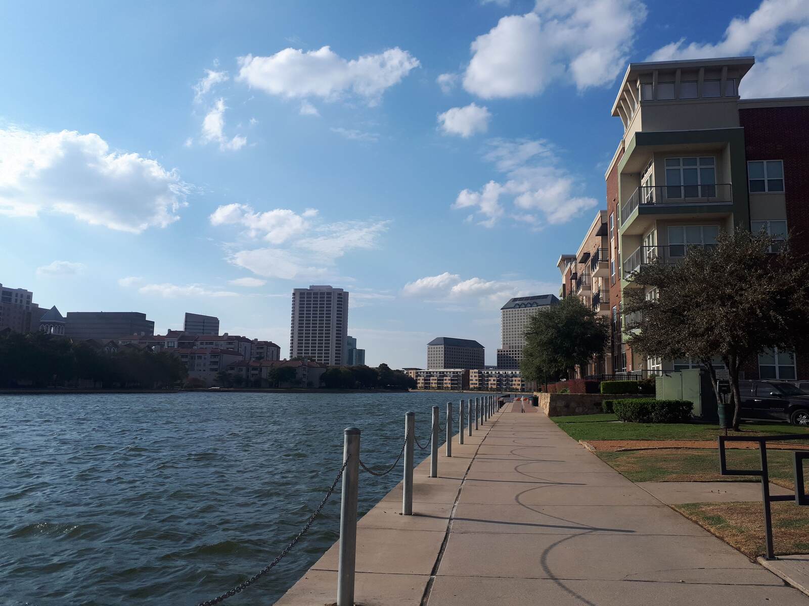 Paved lakeside path running past apartment buildings