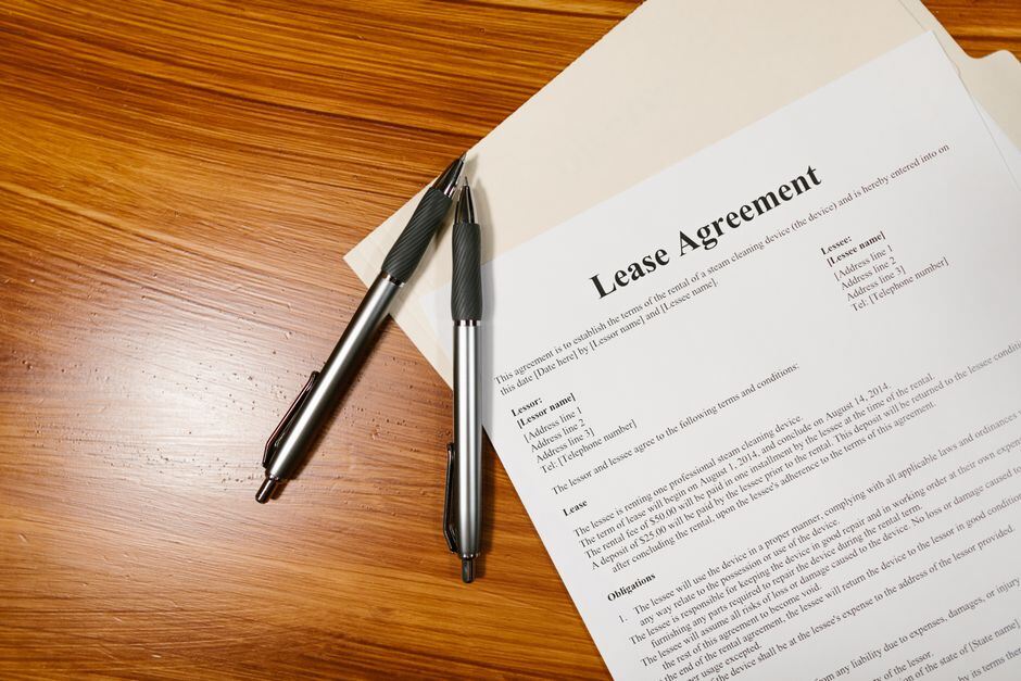 Lease agreement pages and two pens on a wooden desk