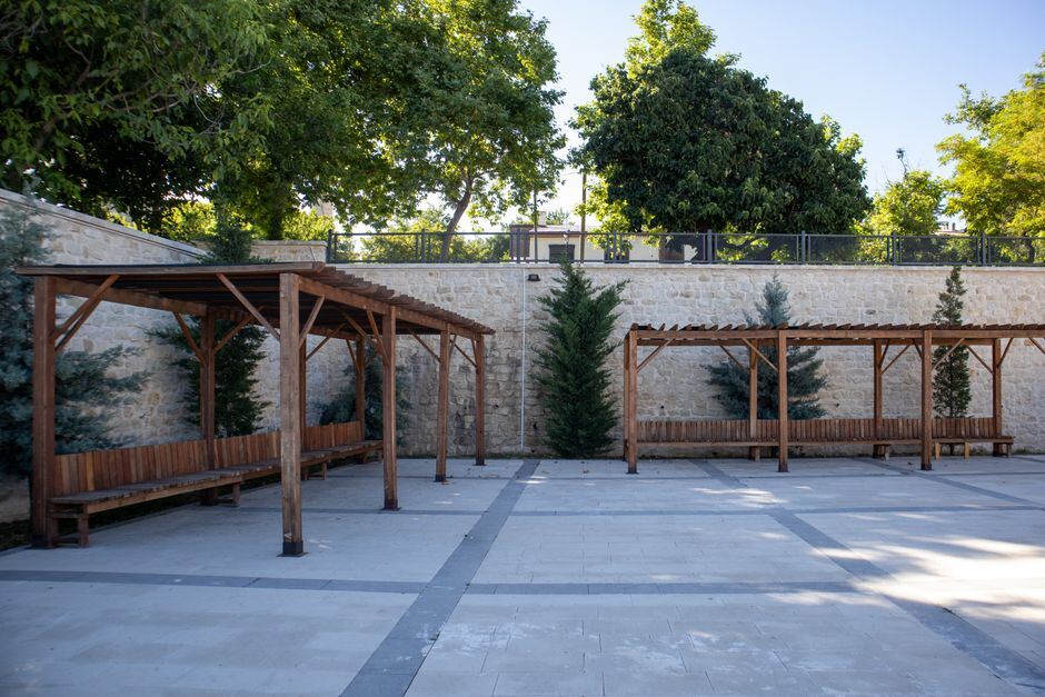 Shaded pergola benches beside a paved courtyard